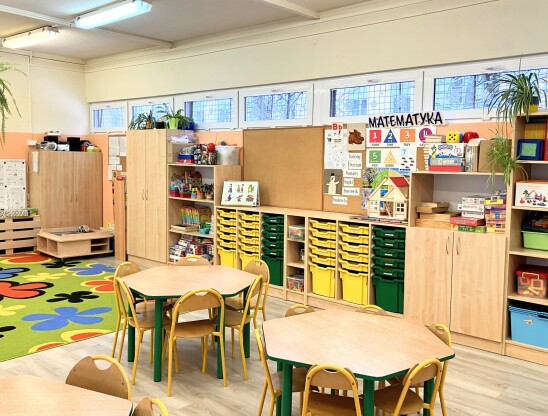 Sala przedszkolna z kolorowym dywanem i półkami z zabawkami